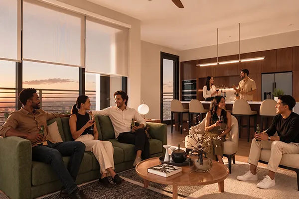 Friends gathering in an Uptown Tucson residence living room at sunset, sharing drinks with a mountain view through floor-to-ceiling windows.