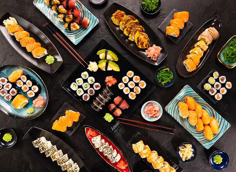 Assortment of sushi rolls on dark platters