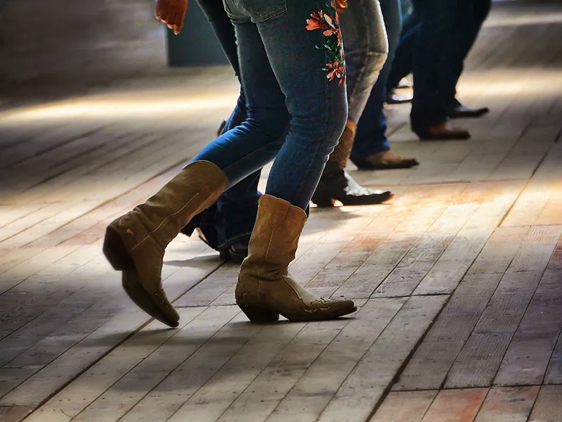 Dancers in cowboy boots on a wooden dance floor