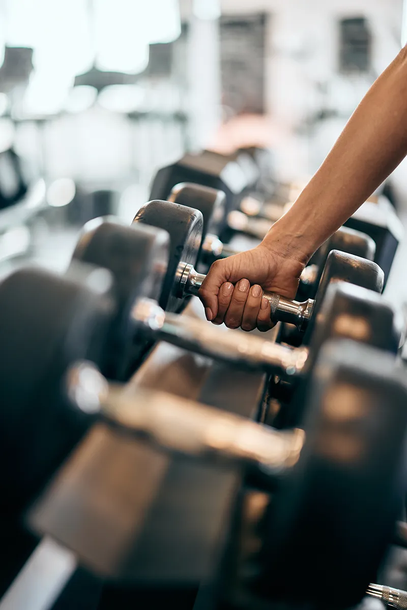 Hand lifting a dumbbell from a rack