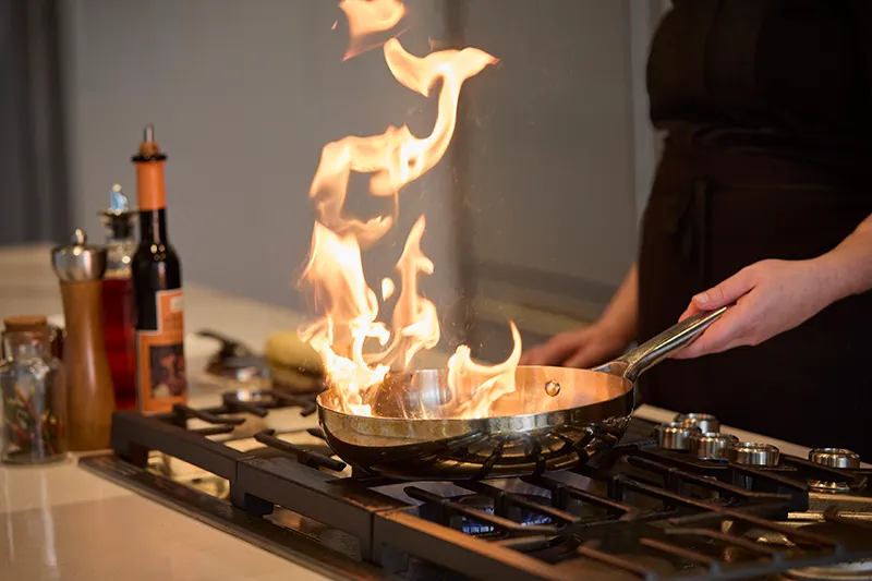 Chef flambéing a pan in a restaurant kitchen