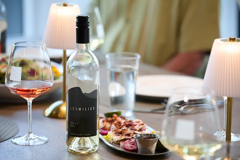 Glass of rosé and a bottle of wine with small plates