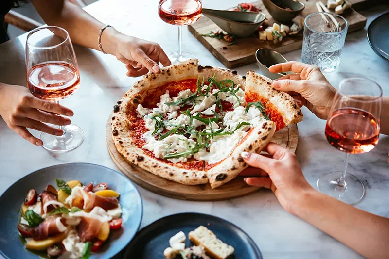 Friends sharing pizza and rosé