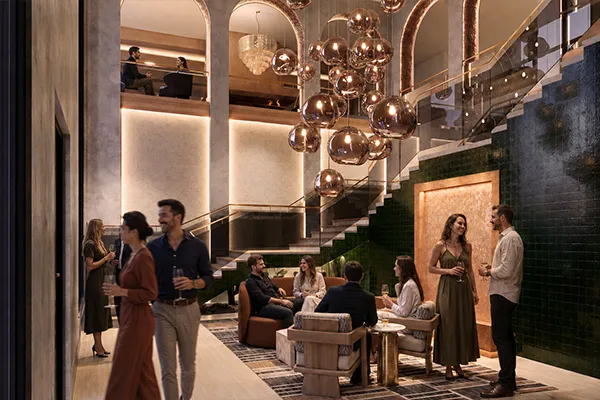 Guests mingling with drinks in the Uptown Tucson lobby lounge, beneath a sculptural pendant chandelier and arched ceilings.